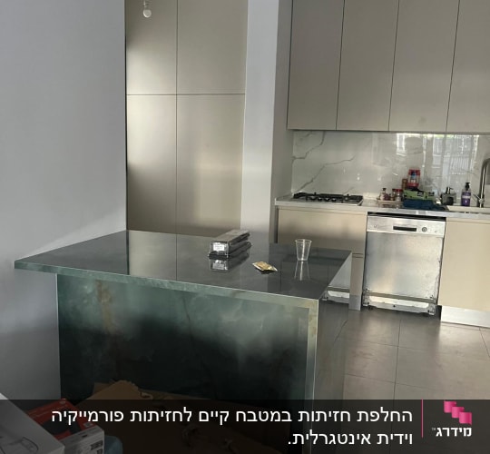 מטבח עם ארונות בהירים, שיש כהה ומכשירי חשמל